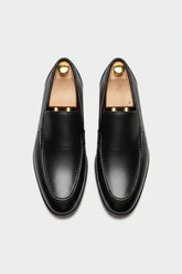 Black slip-on leather tuxedo shoes with textured finish and elegant design.